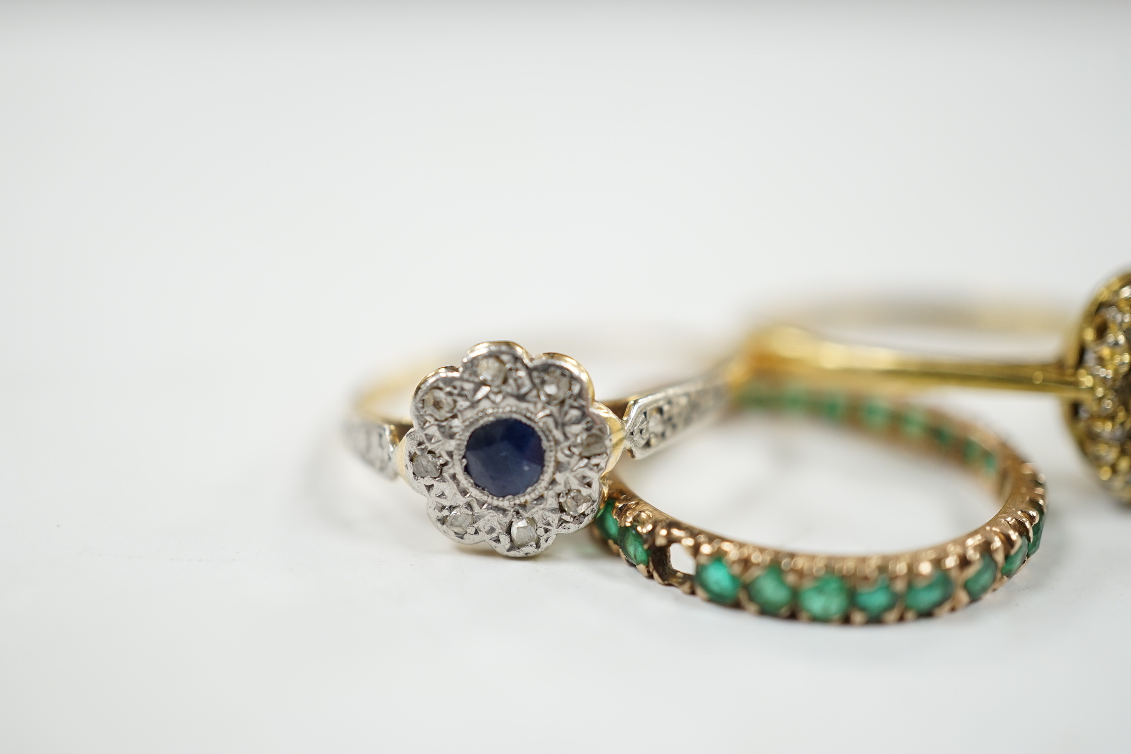 A 1920's 18ct and plat, sapphire and diamond set flower head cluster ring, size L, a 1960's 18ct gold sapphire and diamond set oval cluster ring and a yellow metal and emerald chip set full eternity ring, gross weight 6.